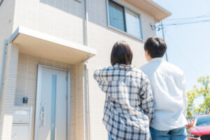 戸建て住宅の外観を確認する夫婦の後ろ姿