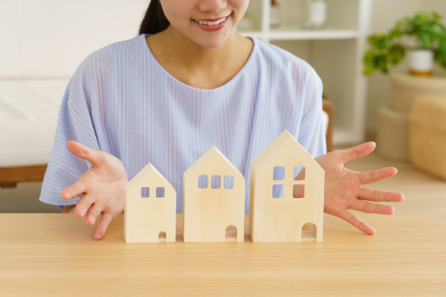 複数の住宅模型から理想の住まいを選ぶ女性